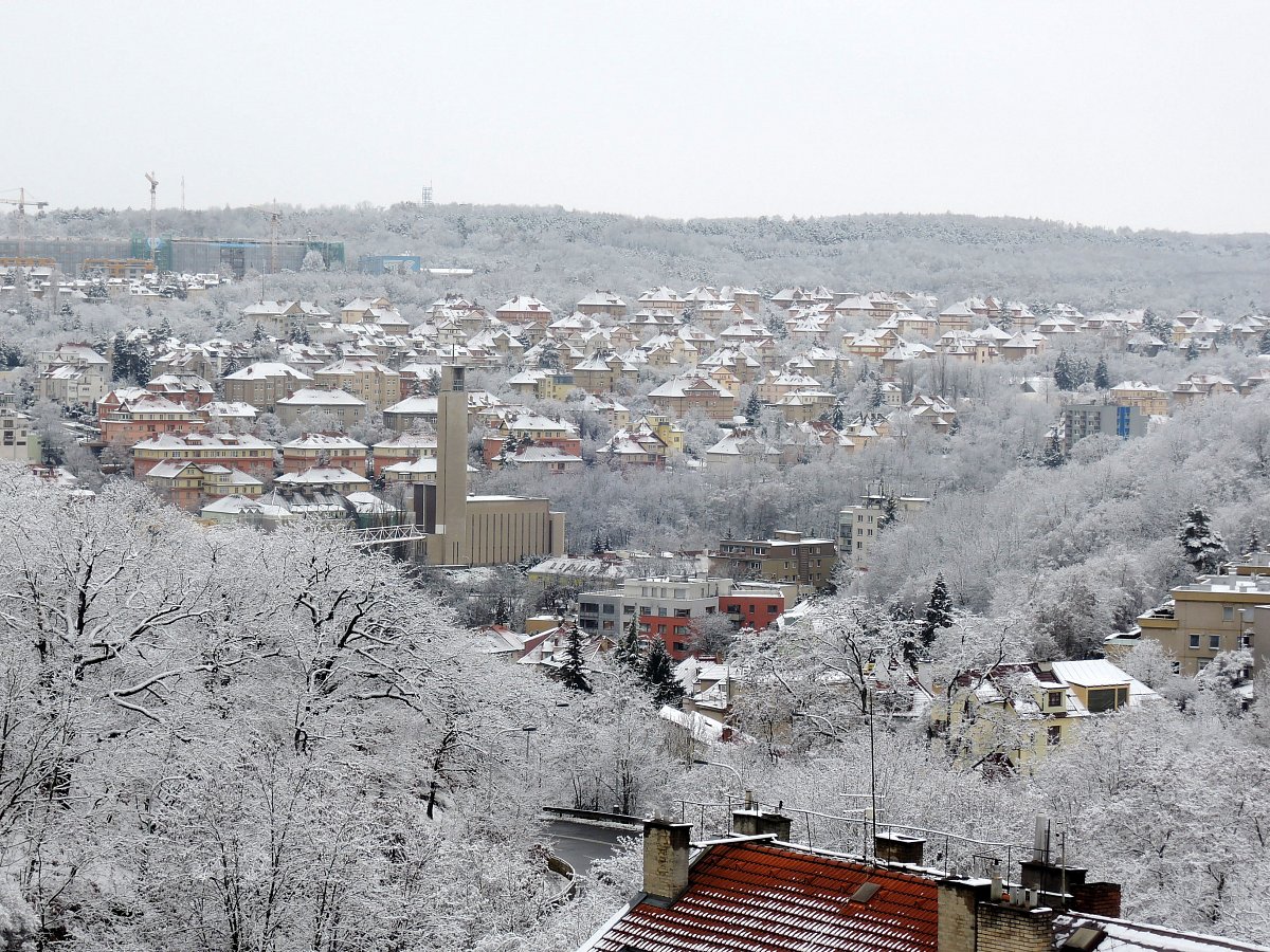 Zasněžené Košíře, nad nimi Jinonice, na obzoru lesík v Nových Butovicích.