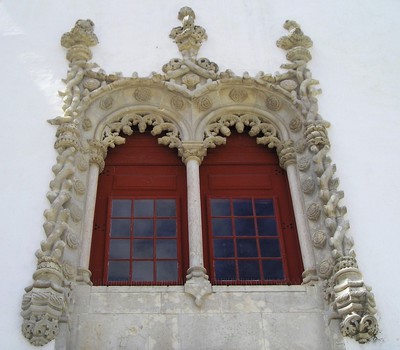 Detail okna s precizně vytesanými jemnými prvky manuelského slohu.