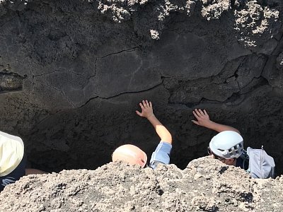 Turisté v jedné z prasklin v zemi po erupci sopky