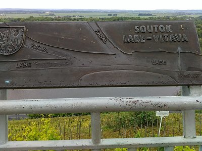 Kovová deska na vyhlídce znázorňuje pohled na kanál i soutok Vltavy a Labe