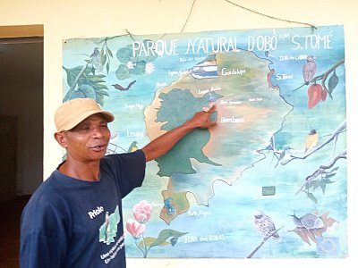 Lionel před mapou ostrova ukazuje, kde se nachází botanická zahrada